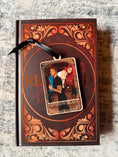 Load image into Gallery viewer, Tarot Card ornament titled "The Shadowbeast" with black ribbon and book underneath.