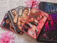 Load image into Gallery viewer, set of four tarot cards with various colors and character, the top labeled "Hellcate" on a book titled "Madison Kate" with flowers and book pages in the background.