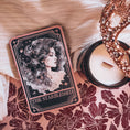 Load image into Gallery viewer, A Tarot Card "The Starblessed" with an image of a celestial woman printed on it with a candle and blanket in the background