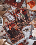 Load image into Gallery viewer, A decorative shelf sign featuring the 'The Future King' tarot card on the left, and "The Second Daughter" tarot card on the right, from the Blood and Ash series, with a book stack, crown, and decorative