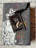 Load image into Gallery viewer, Tarot Card ornament titled "The Witchling" with black ribbon and book underneath.