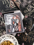Load image into Gallery viewer, A postage stamp with two men embraced titled "Everland", atop a book collection of black books