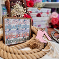 Load image into Gallery viewer, Sign with Chestnut Springs book titles and boots with flowers printed on it. Books and flowers in the background.