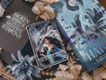 Load image into Gallery viewer, A 'Moonplume' Tarot Card featuring an illustration of a dragon ad a woman, placed next to the book 'When the Moon Hatched' by Sarah A. Parker, with a decorative background.