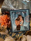 Load image into Gallery viewer, A postage stamp featuring artwork of a romantic scene, with a book titled 'When the Moon Hatched' by Sarah A. Parker, and decorative flowers in the background.