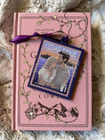 Load image into Gallery viewer, Stop on ornament that reads "Cedar Ridge" with a purple ornament. Pink book in the background.