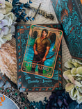 Load image into Gallery viewer, Tarot card featuring 'The King' by Danielle Jensen on a decorative surface with flowers and text.