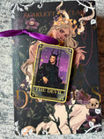 Load image into Gallery viewer, Tarot Card ornament titled "The Devil" with purple ribbon and book underneath.
