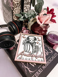Load image into Gallery viewer, Audiophile Book Club Sign. White wooden sign with a lilac border. Bat design with headphones surrounded by flowers, with words below that read "Audiophile Book Club". 2023 FireDrake Artistry®