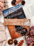 Load image into Gallery viewer, Autumn Spice Shelf Mark™ by FireDrake Artistry® 2024. Woodgrain wood with horizontal white UV printed text that reads "AUTUMN SPICE" and the outline of a pile of books with a pumpkin, flowers, and coffee cup.