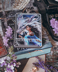 Load image into Gallery viewer, A 'Moonplume' Tarot Card featuring an illustration of a dragon ad a woman, placed next to the book 'When the Moon Hatched' by Sarah A. Parker, with a decorative background.