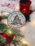 Load image into Gallery viewer, Round shelf sign with a white background. Image of books stacked into a Christmas tree surrounded by lights. The surrounding text reads "Christmas Lights" above in green, with "& Bookish Nights" below in red. © FireDrake Artistry 2025