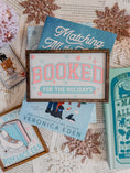 Load image into Gallery viewer, Decorative sign with a wooden frame that reads 'Booked for the Holidays' in pink on a white background. © FireDrake Artistry 2025.
