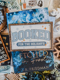 Load image into Gallery viewer, Decorative sign with a wooden frame that reads 'Booked for the Holidays' in blue on a white background. © FireDrake Artistry 2025.