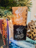 Load image into Gallery viewer, Wooden and black boxes with printed fairy design and 'Lost in Faerie' text, against a Christmas tree background.