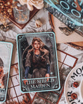 Load image into Gallery viewer, A decorative tarot card shelf sign featuring the card 'The Shield Maiden' with artwork depicting a female figure, surrounded by various items like books, a vase, and decorative items.