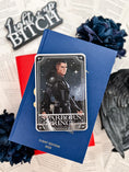 Load image into Gallery viewer, Tarot Card titled "Starboard Prince" with an image of a warrior with a sword printed on it, in front of books by Sarah J. Mass, flowers, and other bookish trinkets.