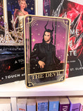 Load image into Gallery viewer, Tarot Card titled "The Devil" with an image of a man with horns in a suit on a bookshelf with books in the background.
