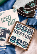 Load image into Gallery viewer, Sign that says "Heston University" with blue hockey jerseys on it. Books and trinkets int eh background.