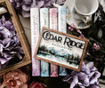 Load image into Gallery viewer, Wooden sign with mountain and lake scene. "Cedar Ridge Washington" printed on the top of the sign. Books, flowers. and teacup in the background.
