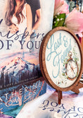 Load image into Gallery viewer, Round wooden sign with the words "Lost & Found" and a compass with flowers printed on it. Sign is placed on a wooden easel. Flowers and books in the background