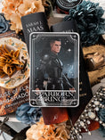 Load image into Gallery viewer, Tarot Card titled "Starboard Prince" with an image of a warrior with a sword printed on it, in front of books by Sarah J. Mass, flowers, and other bookish trinkets.