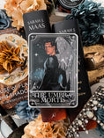 Load image into Gallery viewer, Tarot Card titled "The Umbra Mortis" with an image of a warrior with wings printed on it, on top of books by Sarah J. Mass, flowers, and other bookish items.