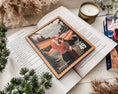 Load image into Gallery viewer, A postage stamp featuring artwork of a romantic scene, on top of an open book with greenery and a candle in the background.