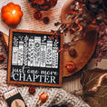 Load image into Gallery viewer, Just One More Chapter Shelf Sign. A wooden shelf sign with black and white artwork featuring book spines and the text 'just one more chapter'. 2024 Fire Drake Artistry.