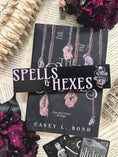 Load image into Gallery viewer, Spells & Hexes Shelf Mark™ by FireDrake Artistry® 2024. Black wooden shelf sitter with purple UV printed text that reads SPELLS & HEXES" to the left of a snake around a vile with flowers.