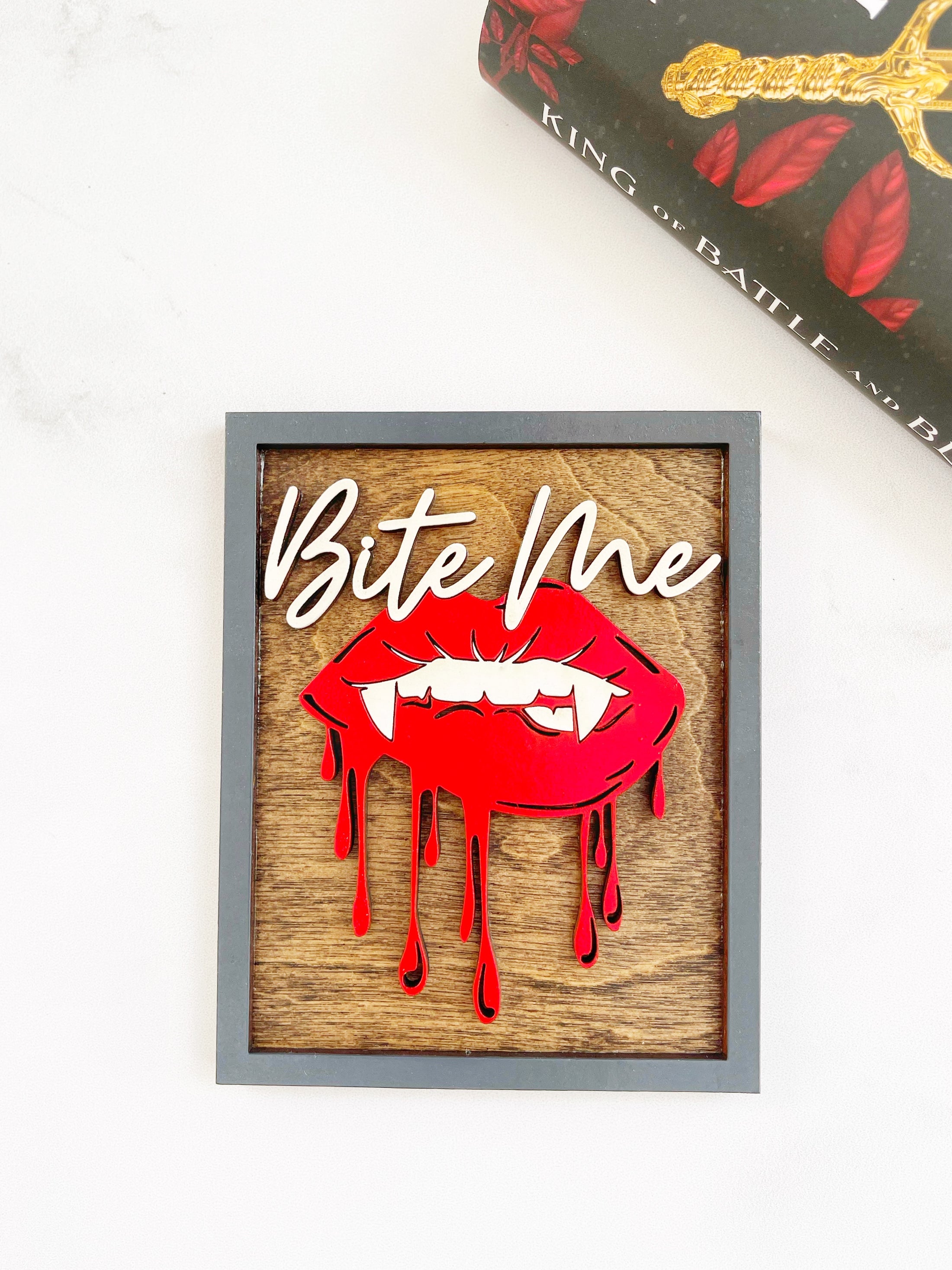 Bite Me Shelf Sign - FireDrake Artistry™ wooden sign with natural background, dark grey frams, white "Bite Me" wording and red vampire lips.