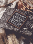 Load image into Gallery viewer, Black shelf sign with white text surrounded by a dark wood border. Graphics of a vial, lavender, rosemary and stars surround text that reads: “Always throw salt over your left shoulder. Keep rosemary by your garden gate. Plant lavender for luck. Fall in love whenever you can.” 
