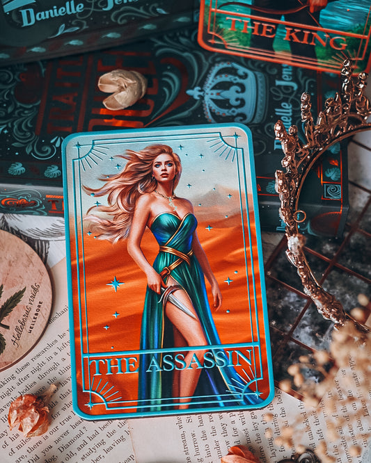 Tarot card featuring 'The Assassin' with decorative items on a textured surface