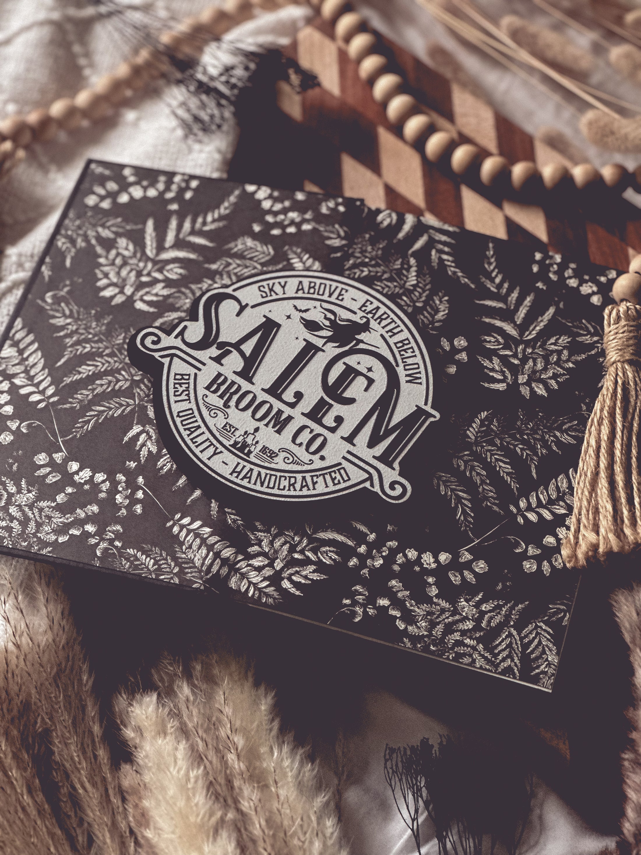 White round sign with black raised text that says “Salem Broom Co”. Featuring a graphic of a witch on a broomstick. ©️FireDrake Artistry®️ 2025