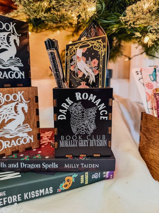 Black box with printed design with 'Dark Romance' text, against a Christmas tree background.