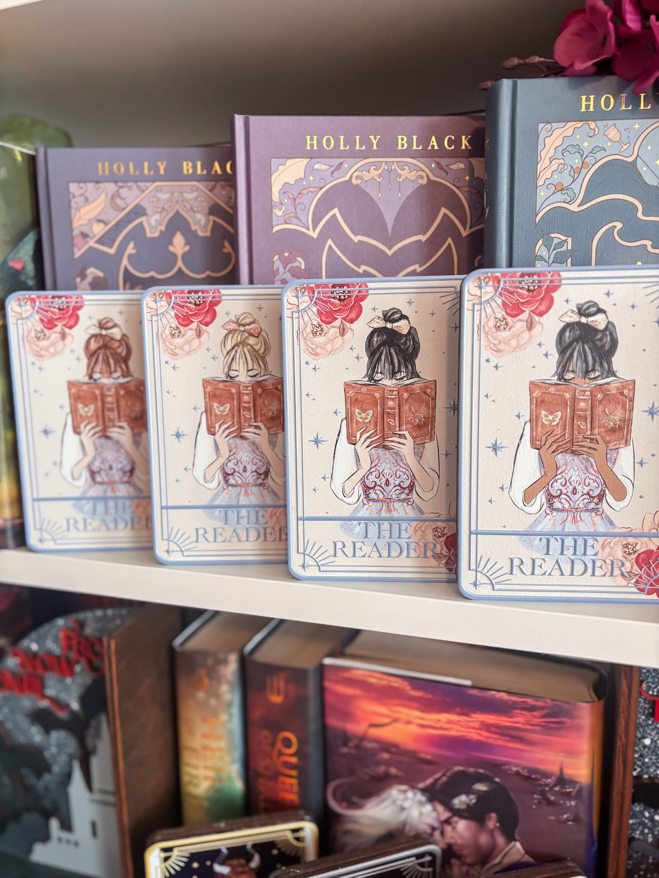 a set of four Tarot cards titled “The Reader” with a girls reading open books in front of a bookshelf with flowers and other decorative items in the background. 