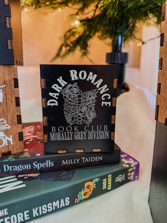 Black box with printed design with 'Dark Romance' text, against a Christmas tree background.