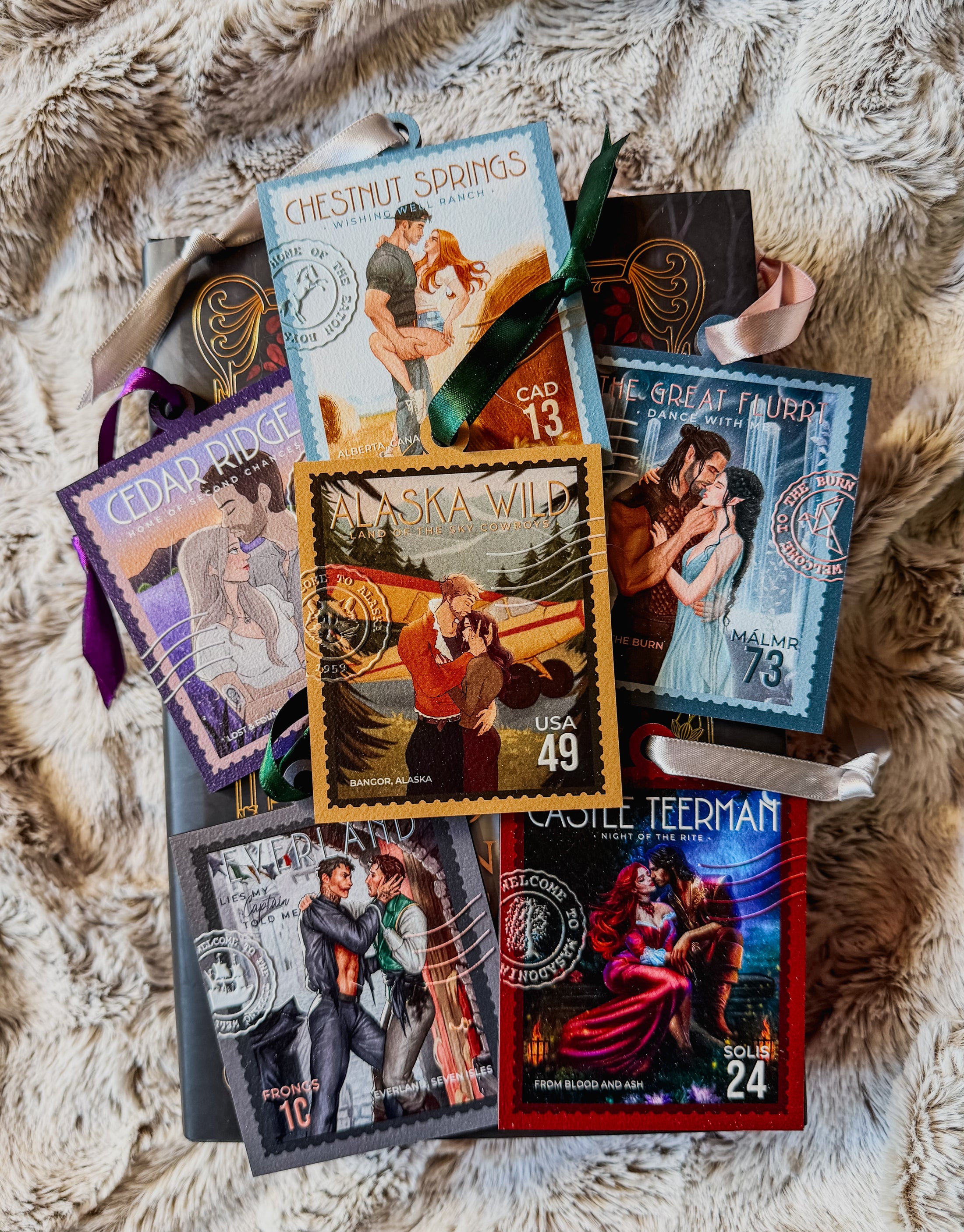 Group of literary stamp ornaments with various titles and couples on the front all with various colors of ribbon. Fur blanket in the background. 