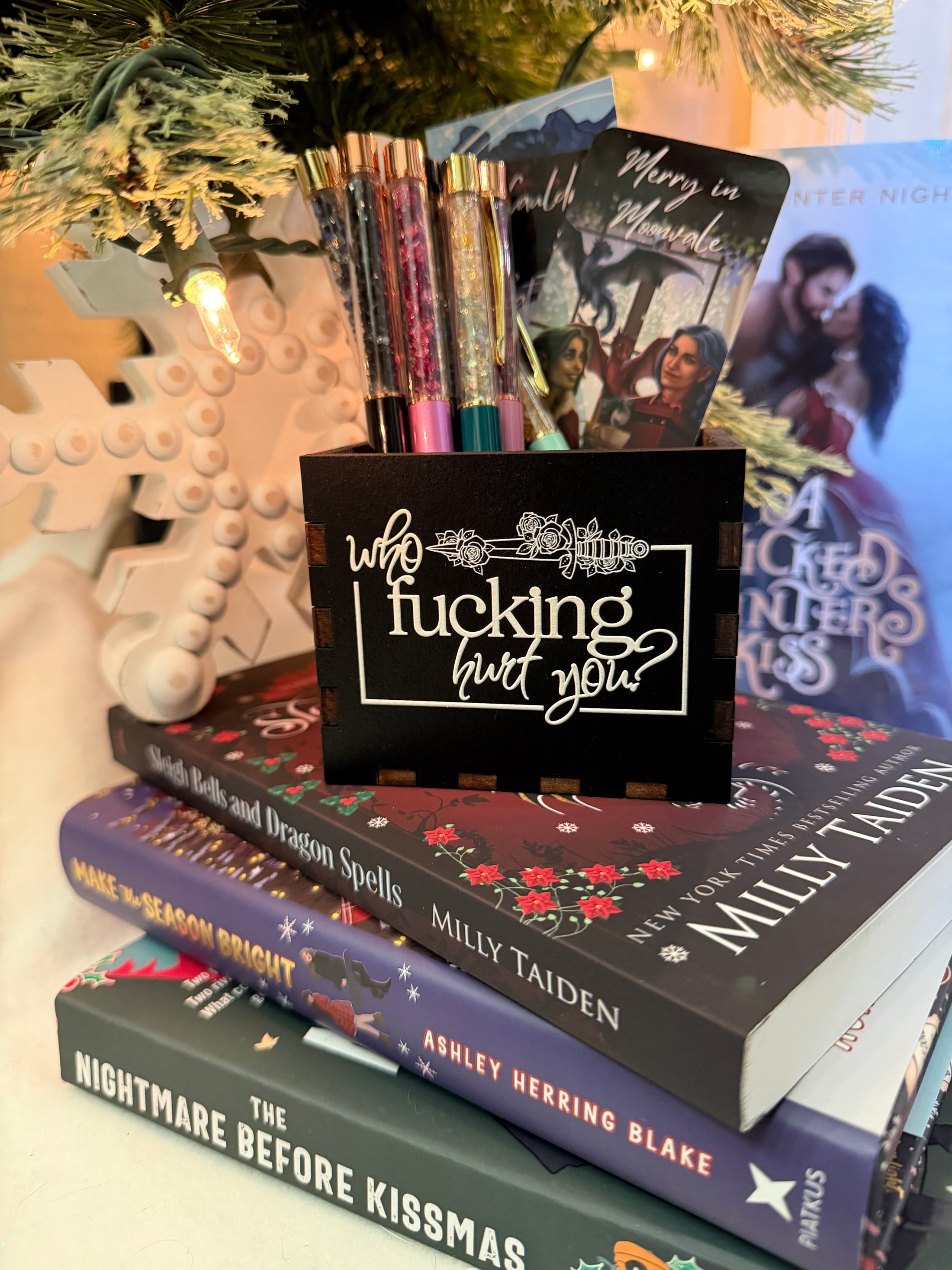 Black, wooden box with “who fucking hurt you” printed on the front. Books and a Christmas tree in the background 