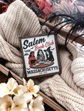 Load image into Gallery viewer, Salem Book Club Sign. White shelf sign with a wood grain border featuring a devil, witch, and skeleton women at a table reading. Top reads “SALEM BOOK CLUB” and the bottom reads “MASSACHUSETTS EST 1692” ©️Fire Drake Artistry 2025
