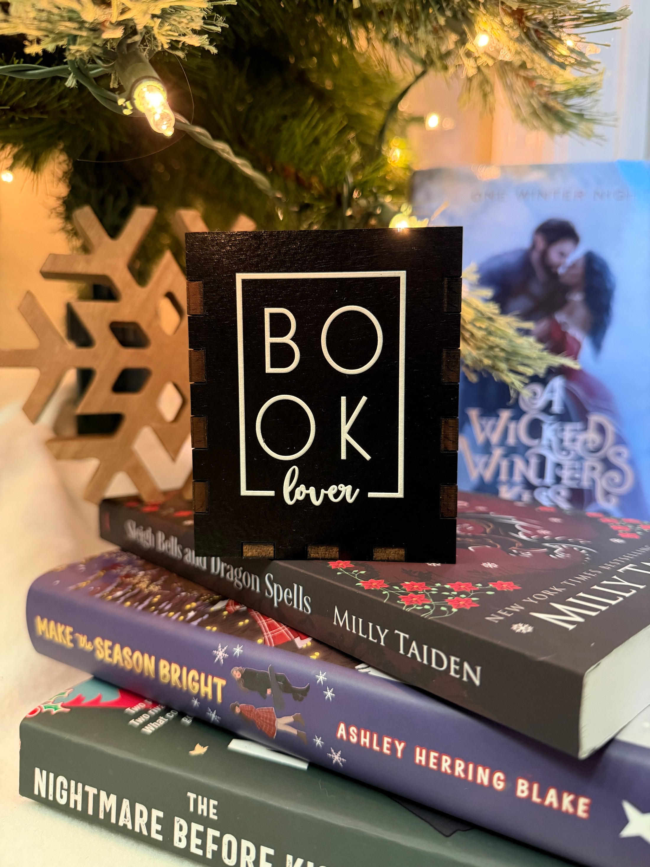 Black box with "Book Lover" printed on them. Bookstack and Christmas tree in the background. 