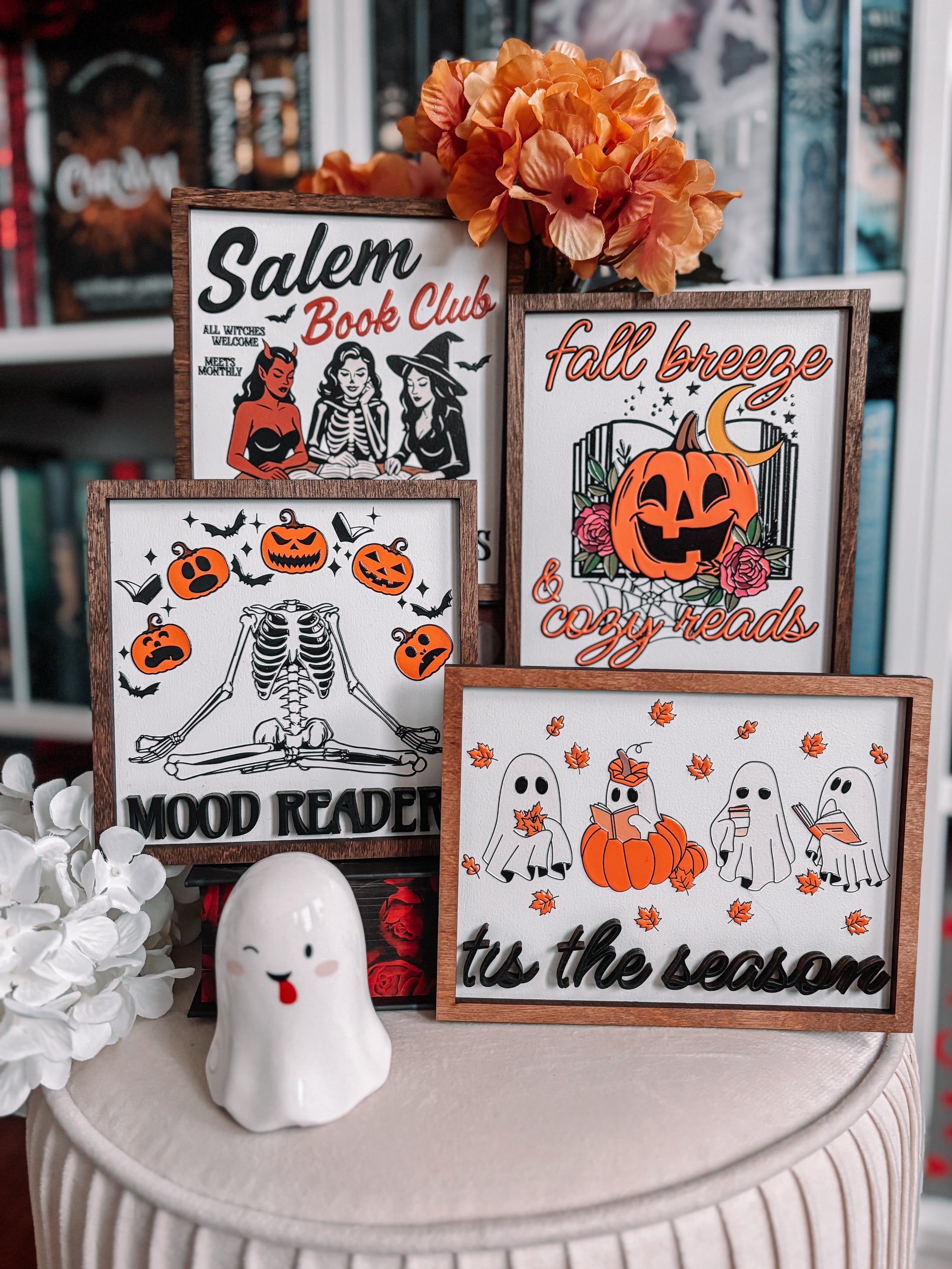 Four Halloween themed shelf signs featuring pumpkins, skeletons, and women in costumes. 