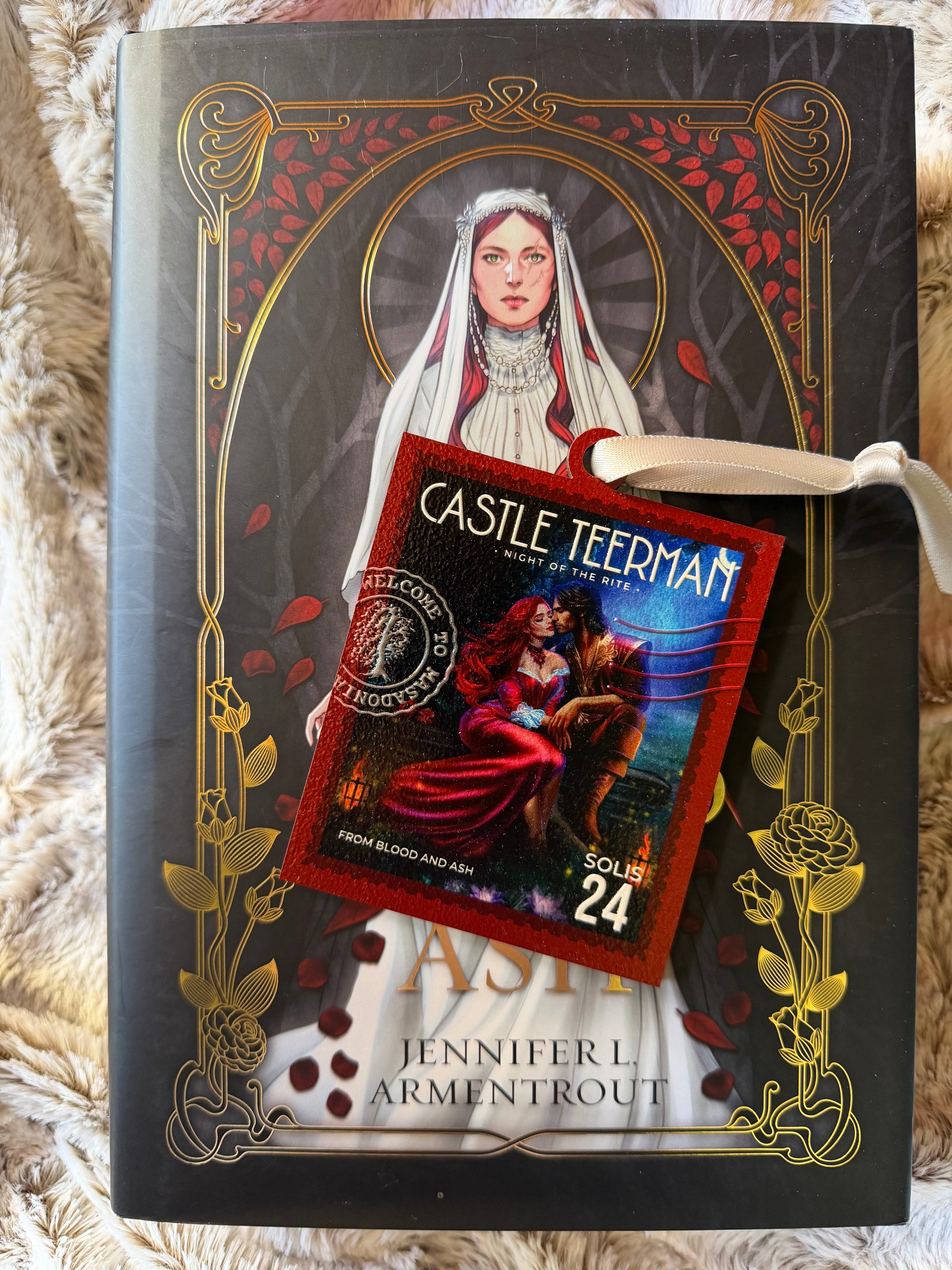 Stamp on ornament with "Castle Teerman" on the top and a silver ribbon book with a bride on the cover in the background. 