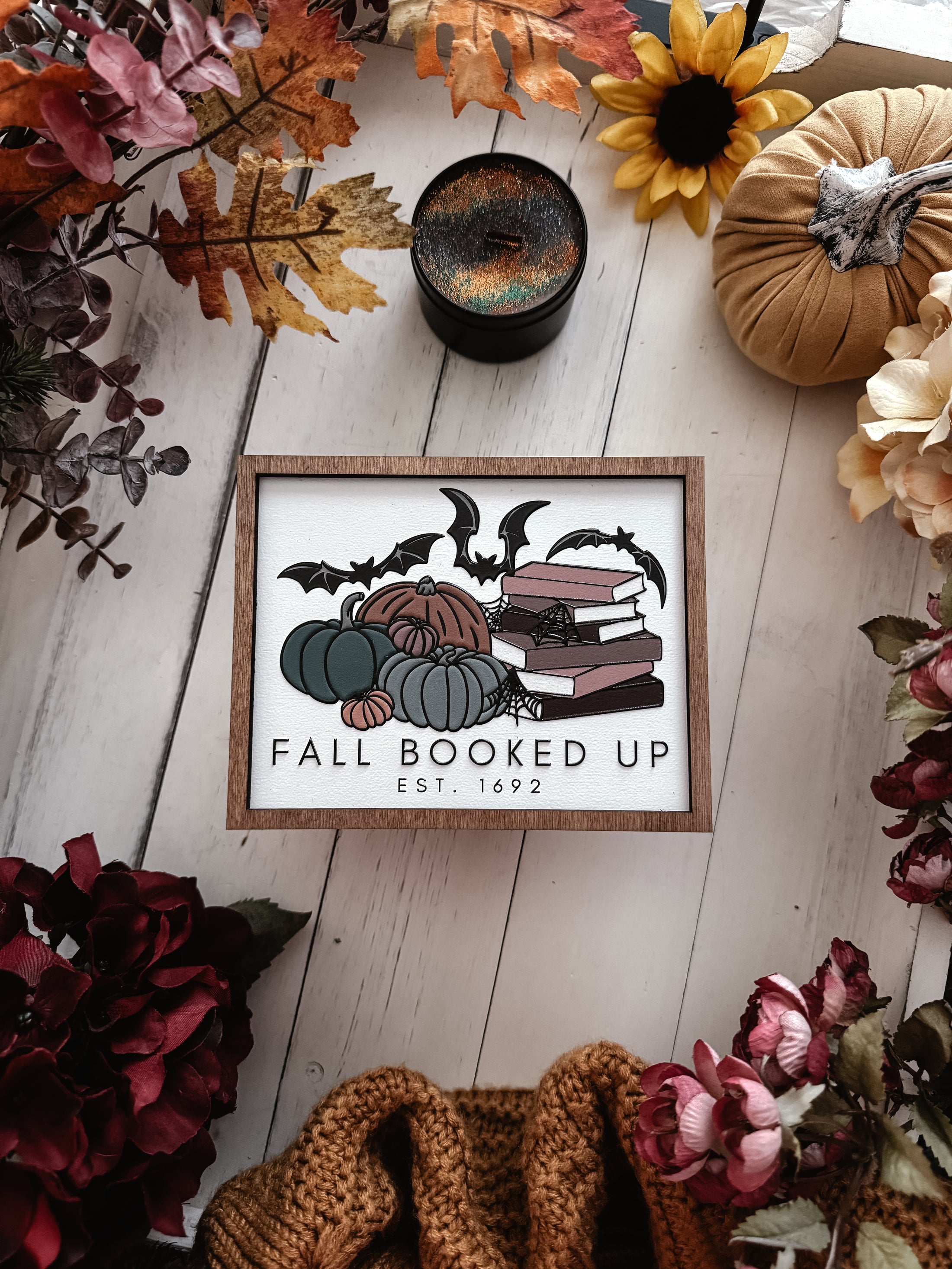 Fall Booked Up Sign - Multicolor Version- ©️ Fire Drake Artistry 2025. Wooden sign with white background and wood stained frame, UV printed design with a cluster of pumpkins beside a stack of books and bats flying around. 