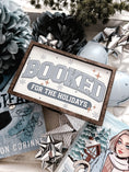 Load image into Gallery viewer, Decorative sign with a wooden frame that reads 'Booked for the Holidays' in blue on a white background. © FireDrake Artistry 2025.
