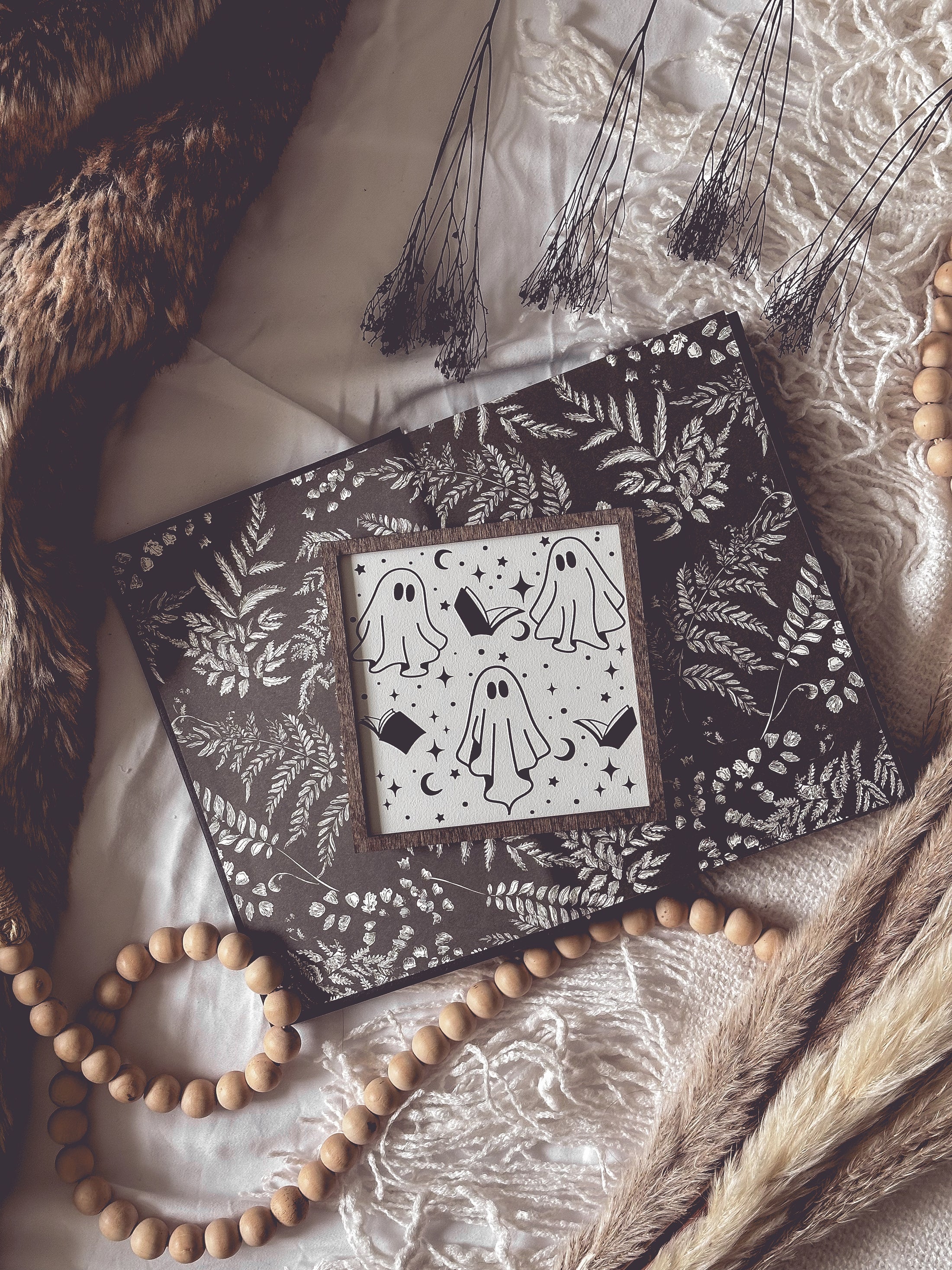 Boo Books Shelf Sign. A white. wooden square sign with a wood frame featuring illustrations of ghosts, books and stars. 2023 FireDrake Artistry®