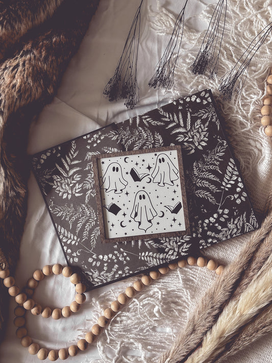 Boo Books Shelf Sign. A white. wooden square sign with a wood frame featuring illustrations of ghosts, books and stars. 2023 FireDrake Artistry®