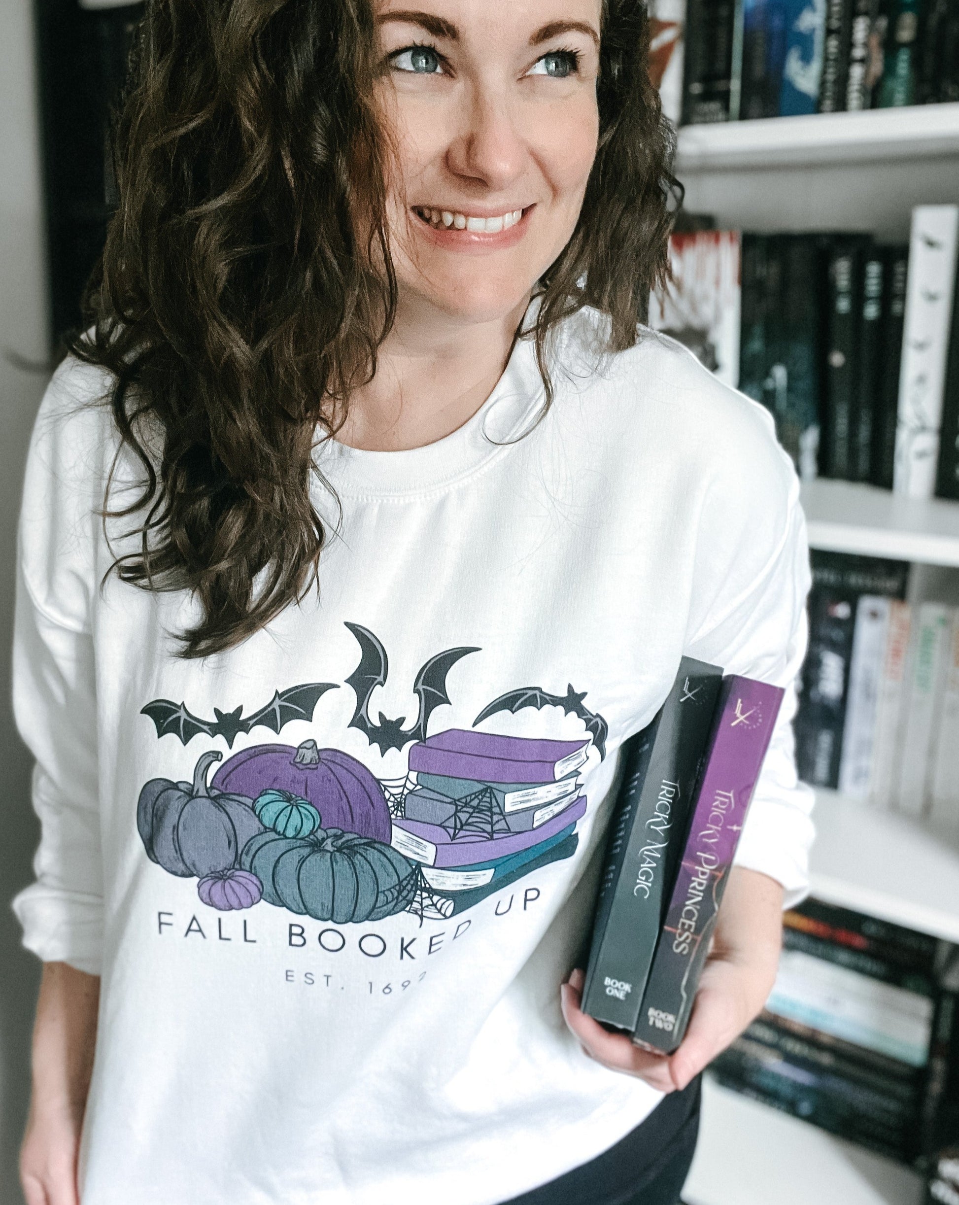 White Fall Booked Up sweatshirt with purple books by FireDrake Artistry™. Photo by @athousandbookishlives
