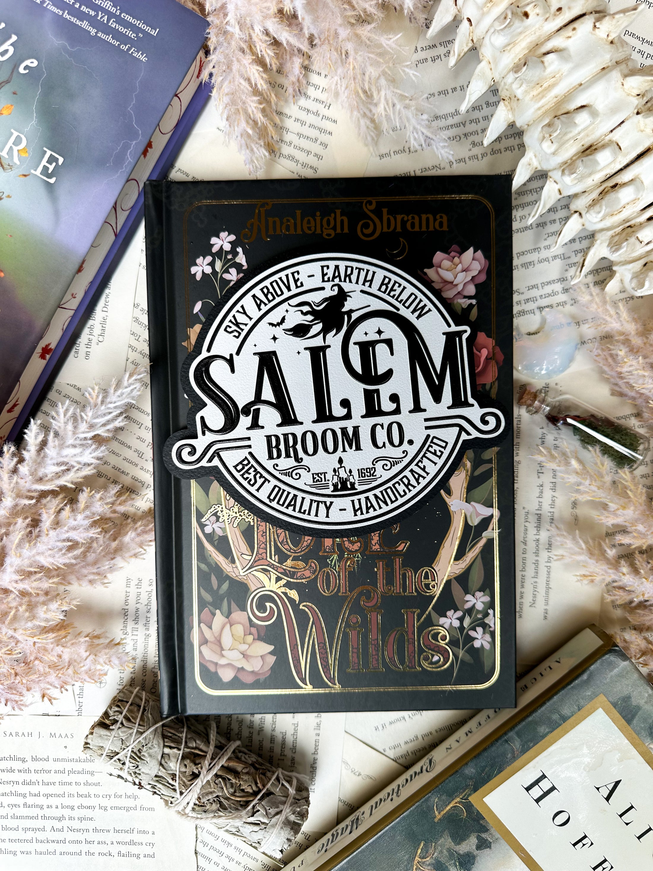 White round sign with black raised text that says “Salem Broom Co”. Featuring a graphic of a witch on a broomstick. ©️FireDrake Artistry®️ 2025