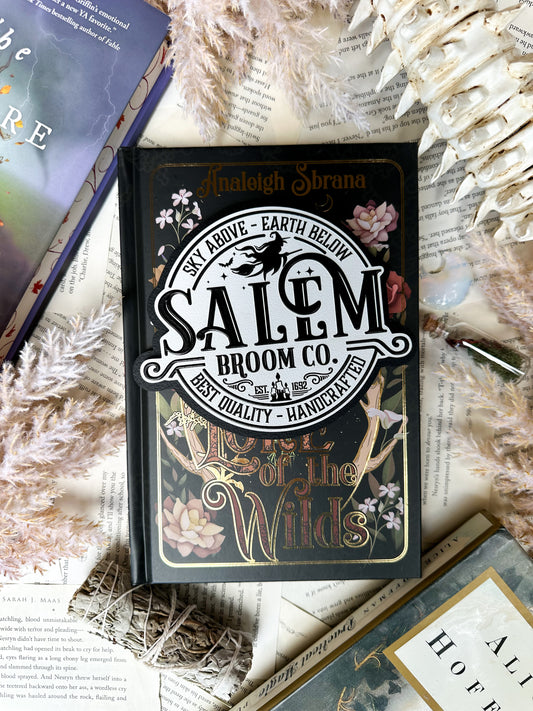 White round sign with black raised text that says “Salem Broom Co”. Featuring a graphic of a witch on a broomstick. ©️FireDrake Artistry®️ 2025